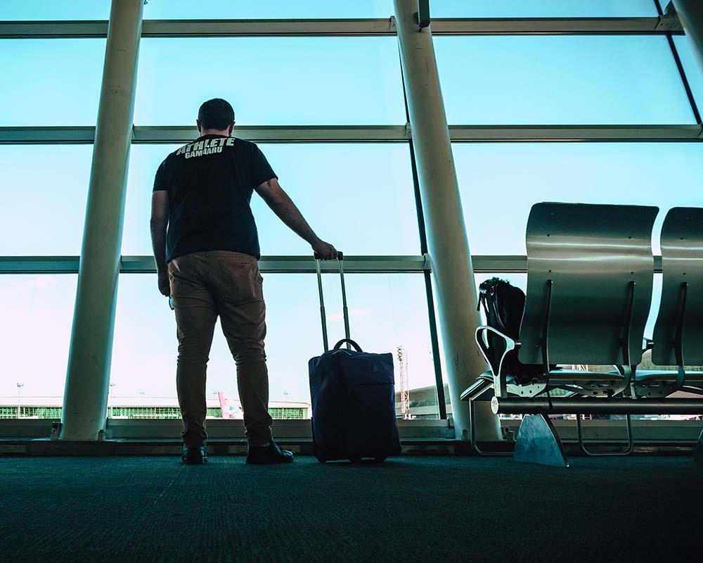 man stood at the airport with his suitcase