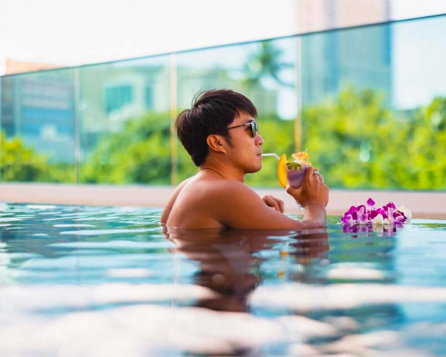 man drinking a cocktail in the pool at the hotel la croix