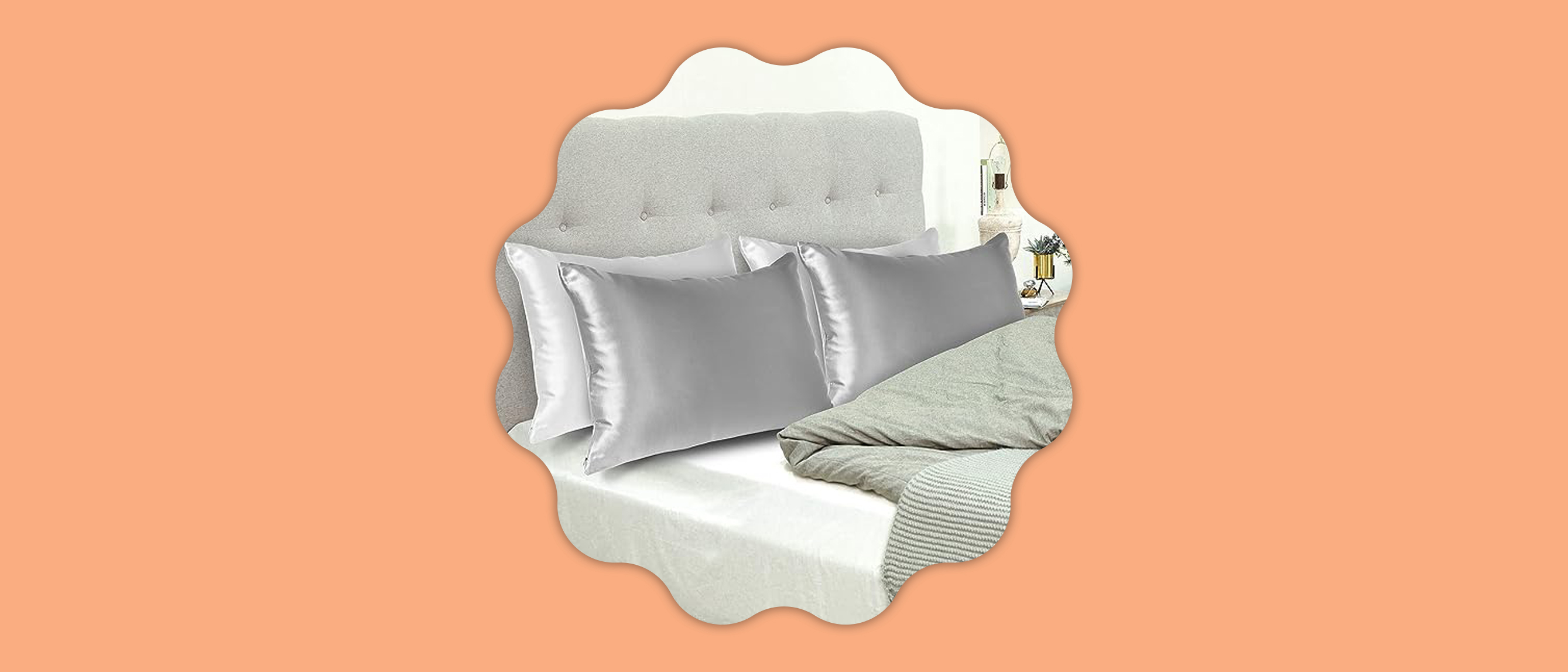 Grey silk pillowcases on a bed against a pastel orange background