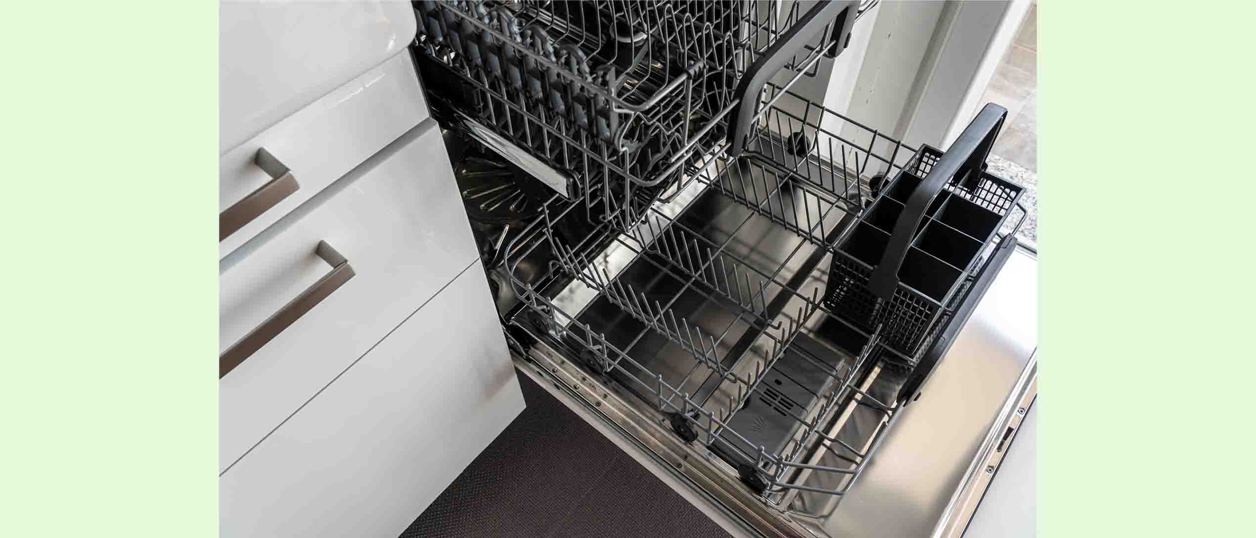 a close up shot of an open and empty dishwasher in a kitchen