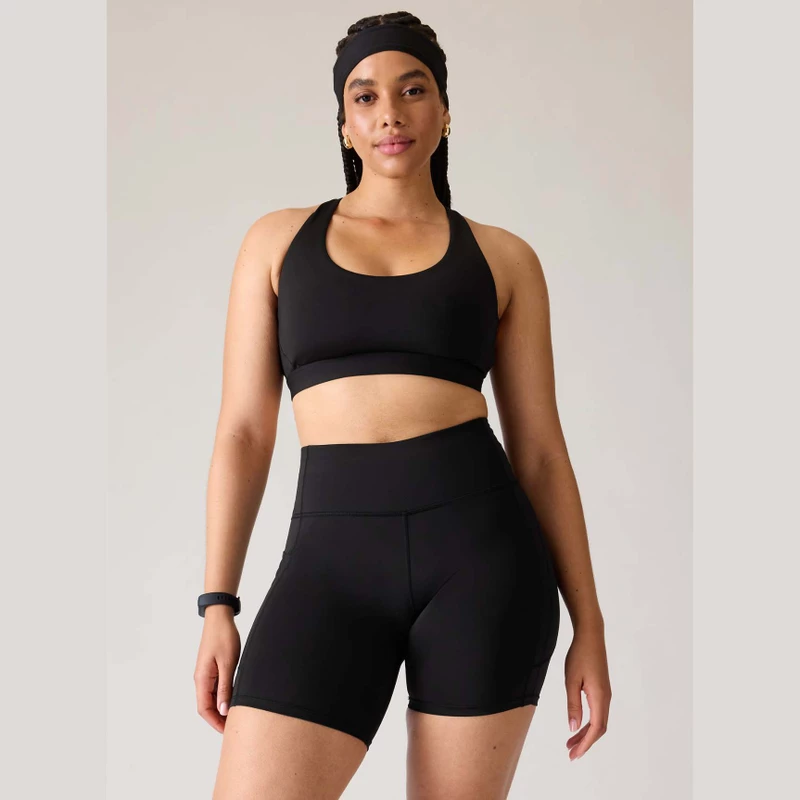 model wearing Athleta Ultimate Bra in black with matching cycle shorts  
