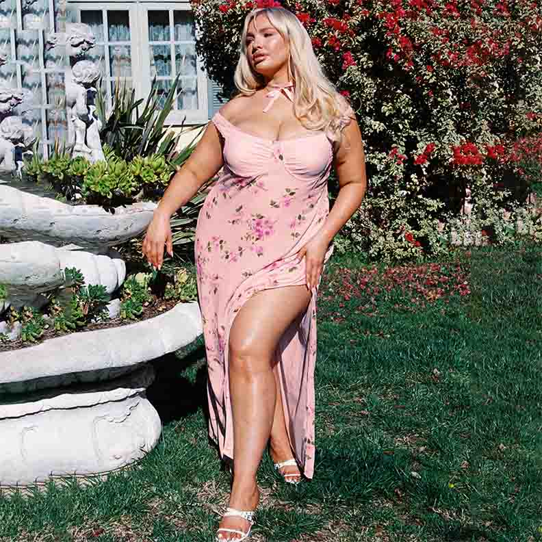 Blonde woman wearing pink floral dress in a garden