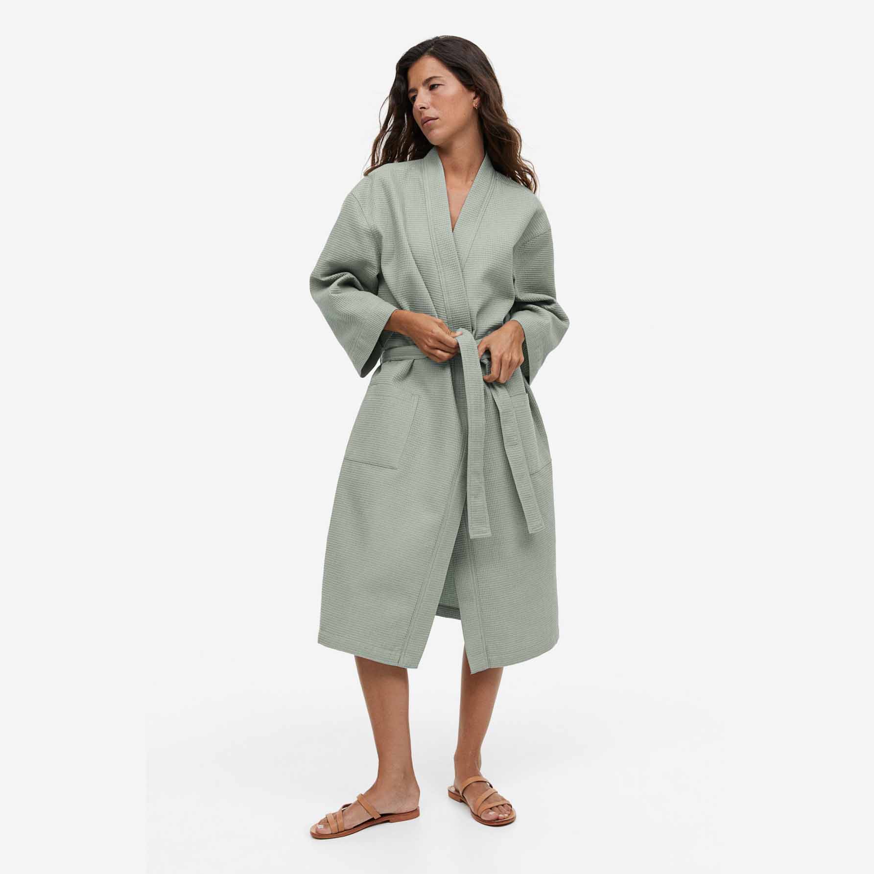 woman wearing a belted robe in light sage green 
