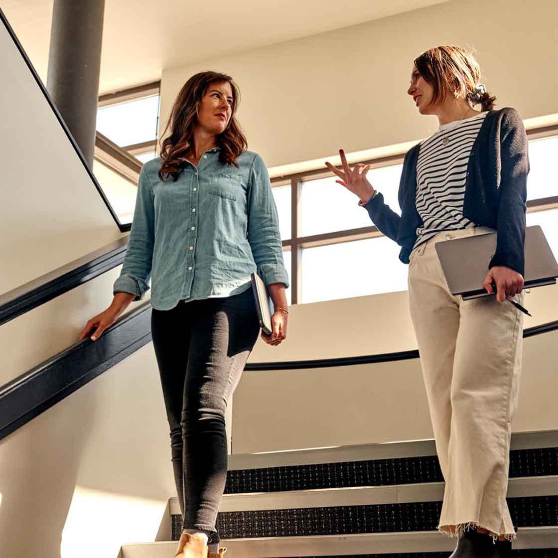 two women walking down the stairs talking to each other 