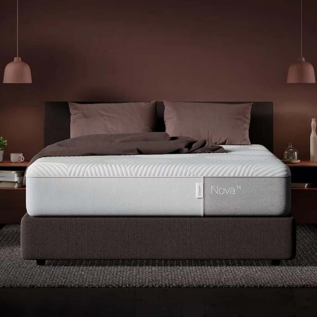 Nova Hybrid Mattress on a brown bed frame with pillows and a throw