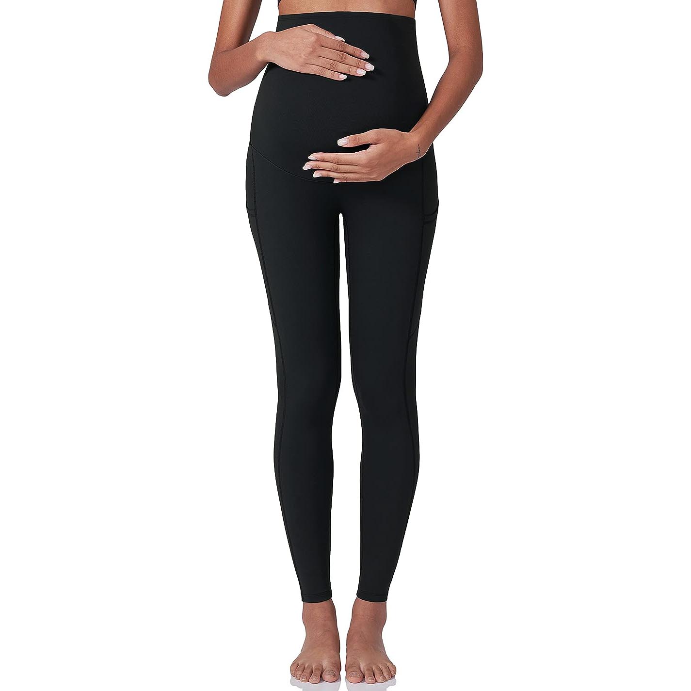 Woman holding belly bump in black leggings