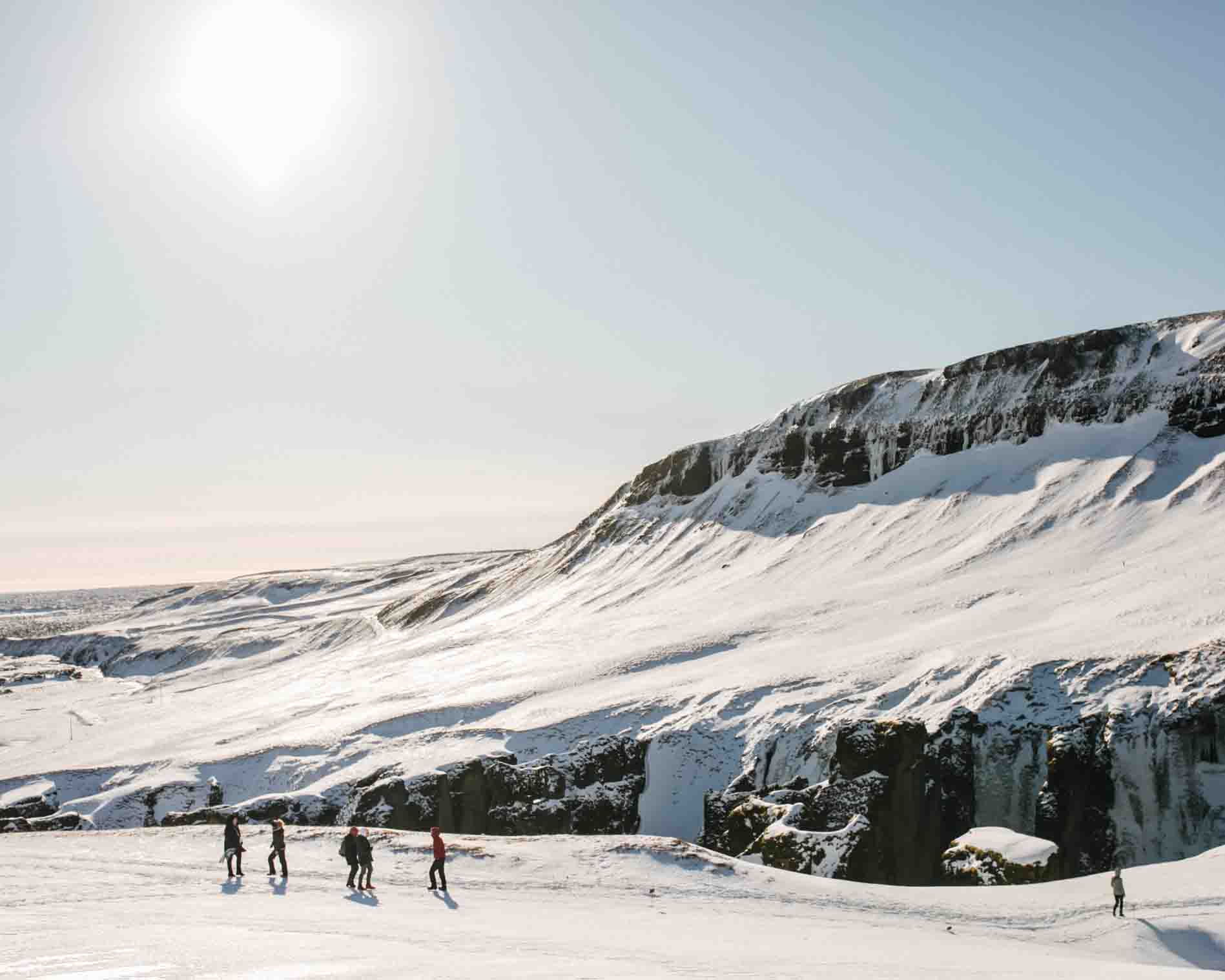a group of people walking on a snow covered mountain trail in Iceland