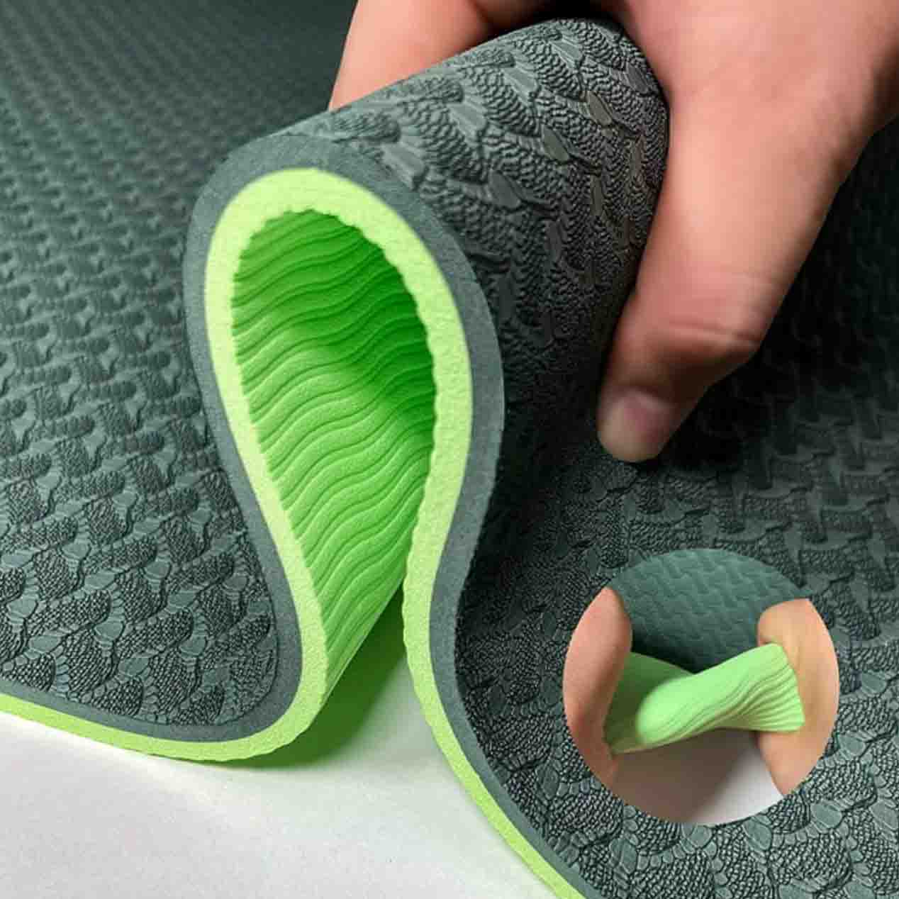 Person squeezing thick green yoga mat