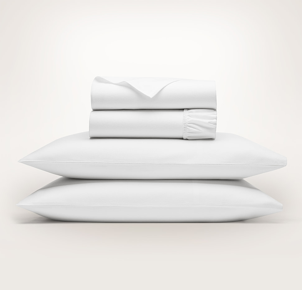 Folded white sheets stacked on pillows