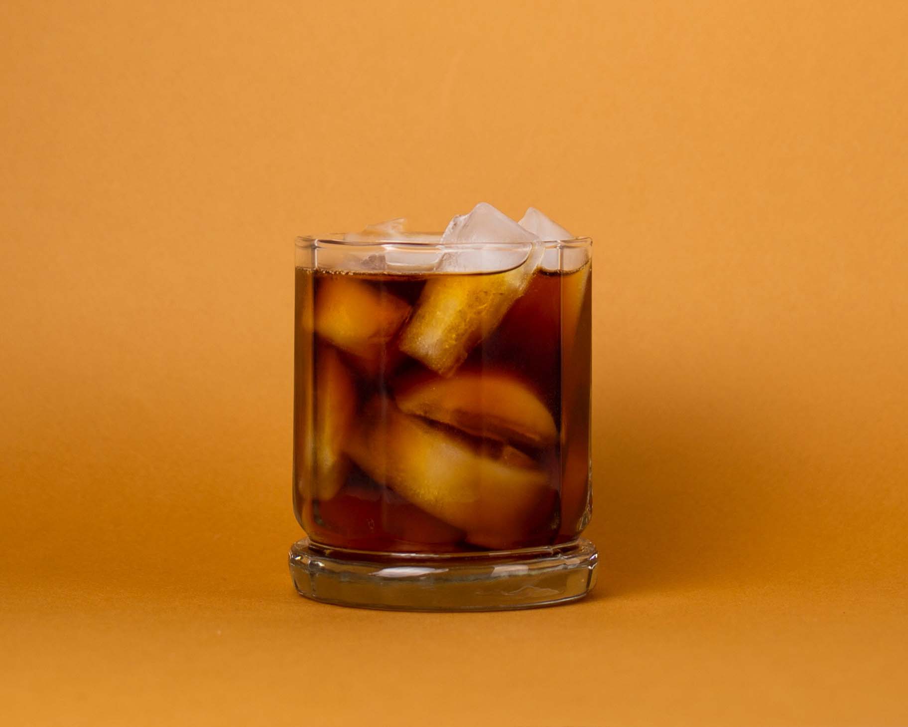glass of cold brew with ice on an orange background