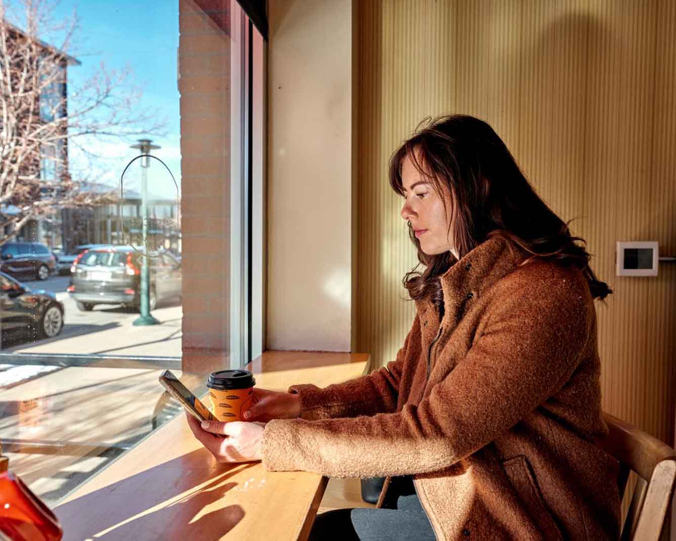 woman sitting at a cafe looking at her mobile phone